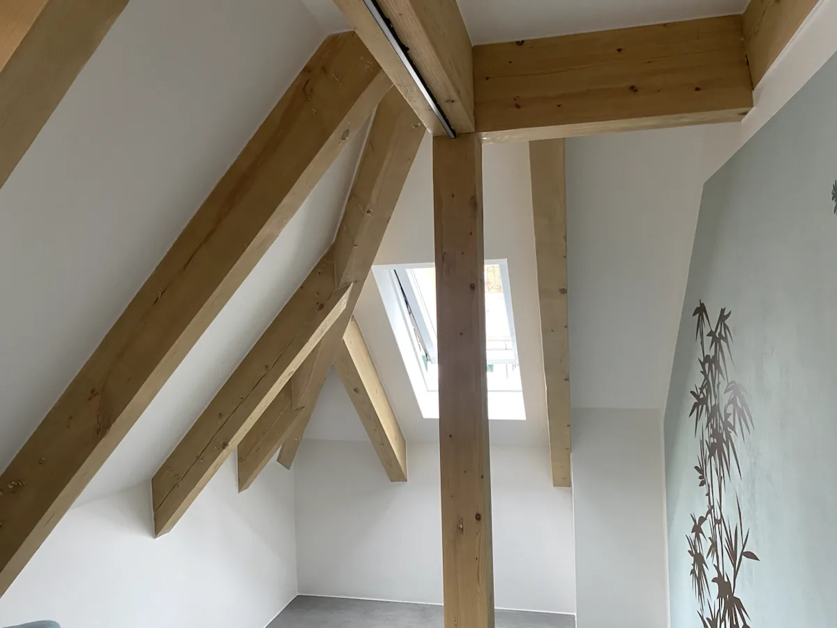 Ausgearbeitete Holzbalken im hellen Dachgeschoss